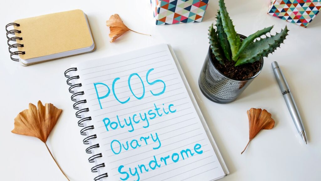 Quaderno con la scritta PCOS accanto a materiale da ufficio, per illustrare pCOS e microbiota vaginale