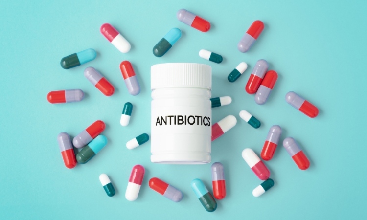 Capsule sparse attorno a un contenitore di antibiotici, per illustrare antibiotici e microbiota vaginale